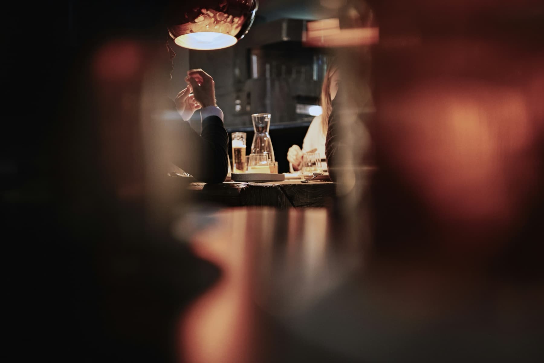 Two people talking across a table in a dimly lit restaurant