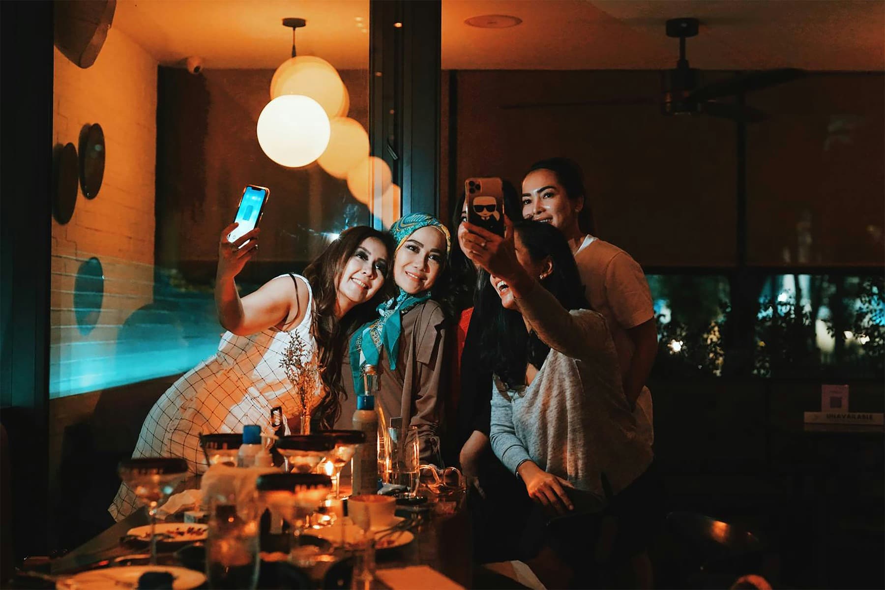 Friends laughing around a table in a warmly lit restaurant