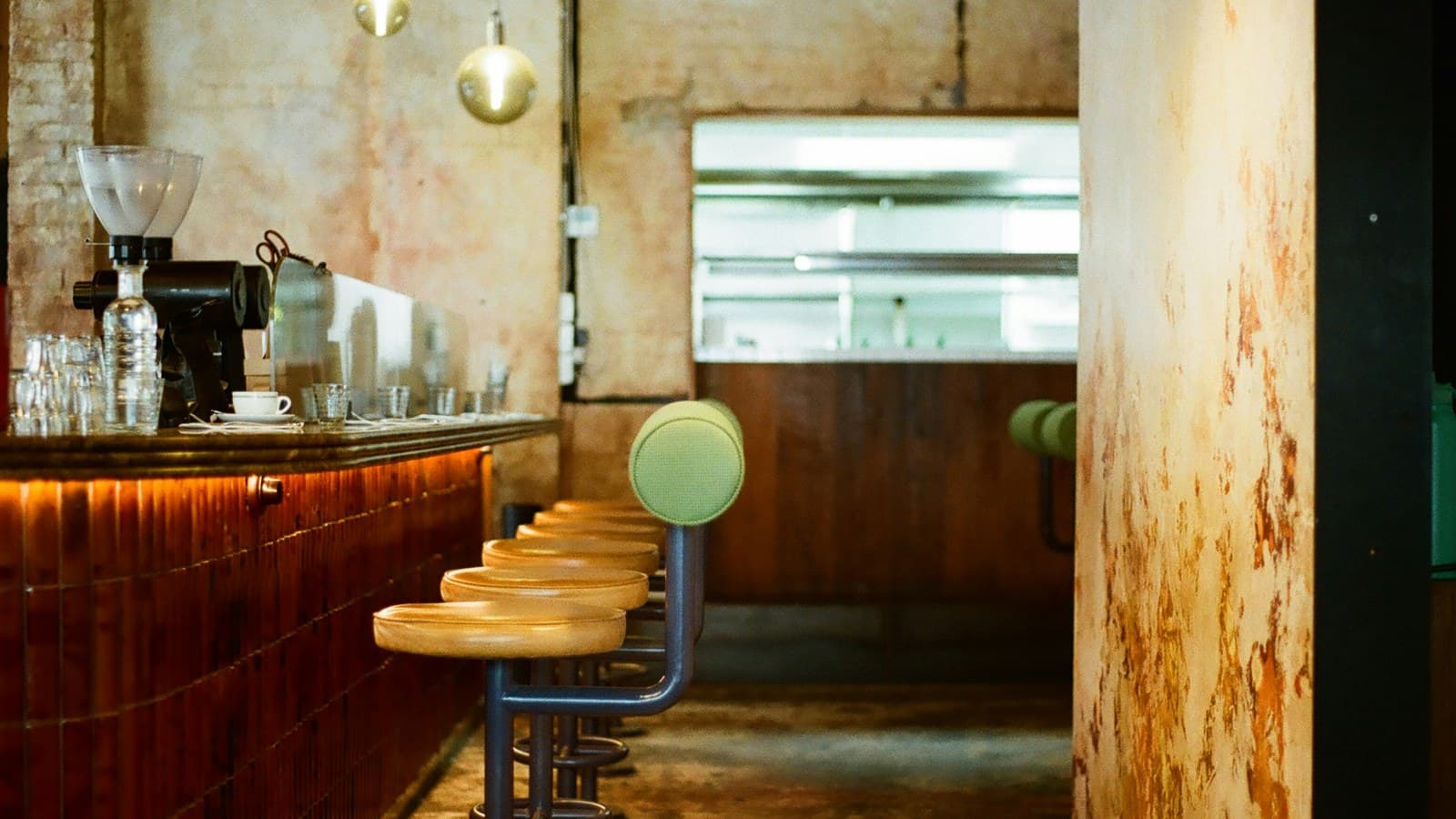 A row of stools along a warm, dimly lit restaurant counter